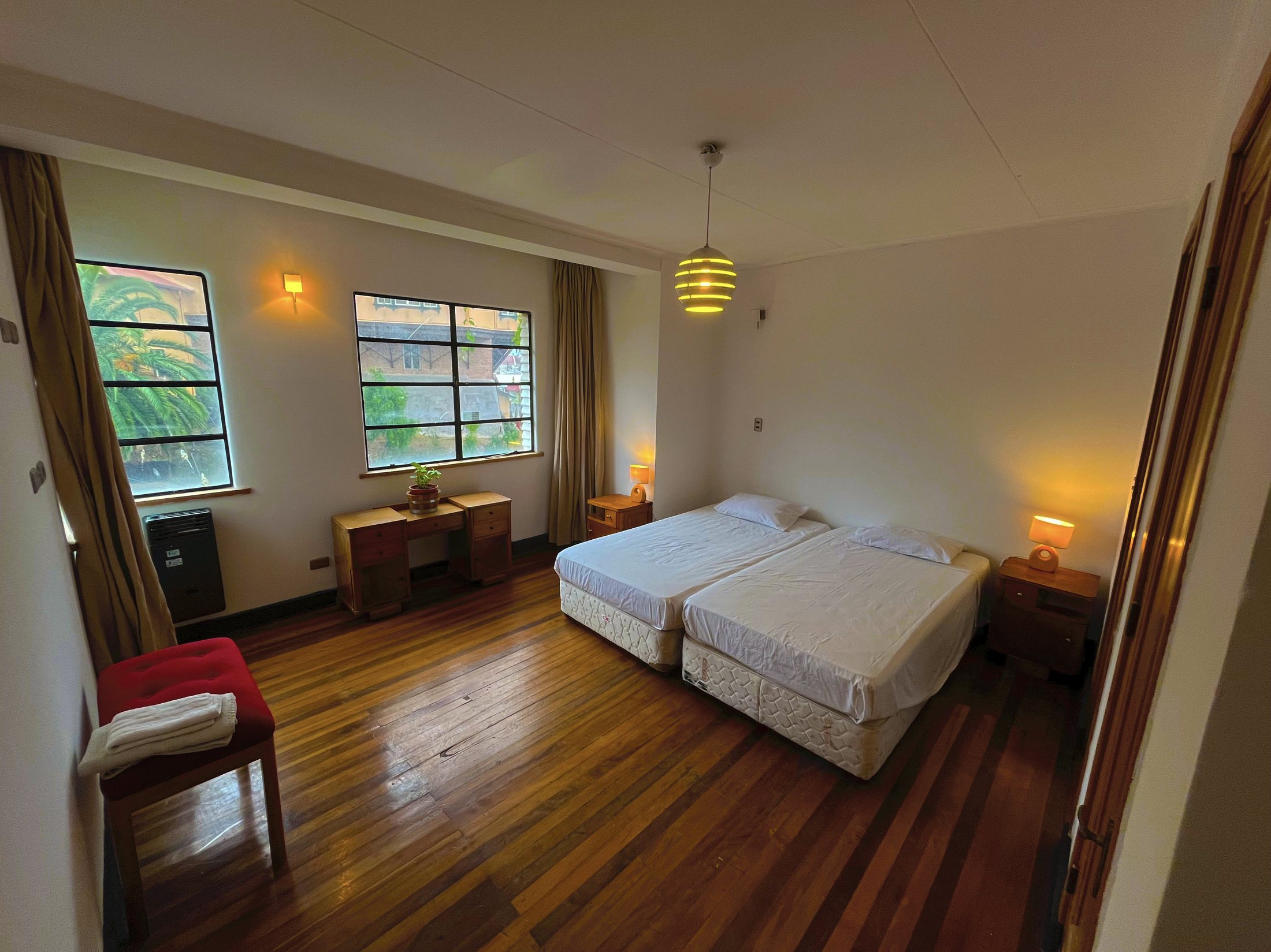 Habitación del hostal con camas, madera cálida y vista hacia Valparaíso